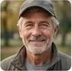'Smiling senior man with a grey beard wearing a baseball cap avatar portrait.
